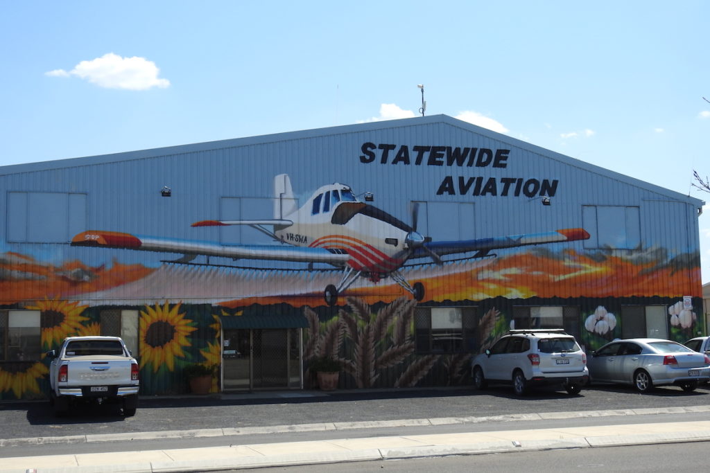 Mural of Moree Statewide Aviation. Mural features a plane flying over fields of sunflowers, wheat and cotton as the sun is setting on the Moree Plains. www.gypsyat60.com