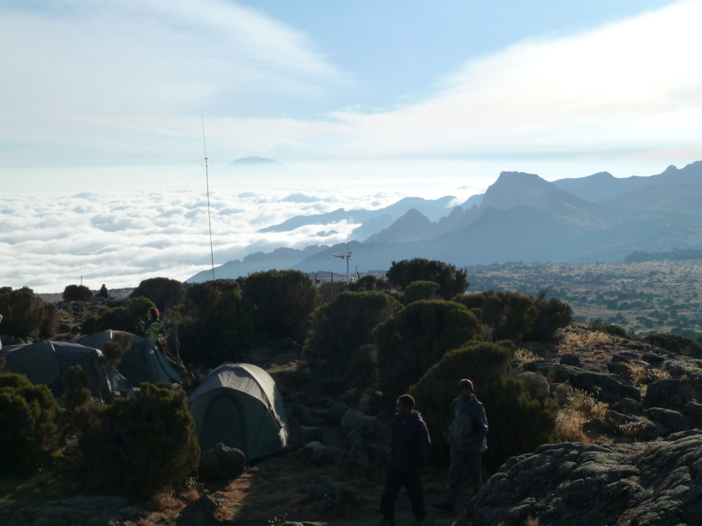 Climbing Mt Kilimanjaro View of Mt Meru peeking through clouds. Taken from Shira Hut Camp Site